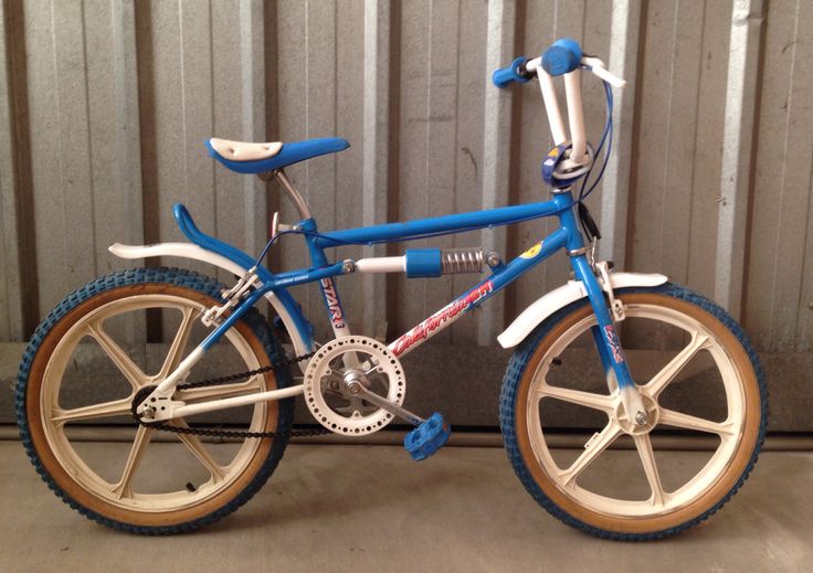 a blue and white bicycle is parked in front of a metal wall with brown spokes